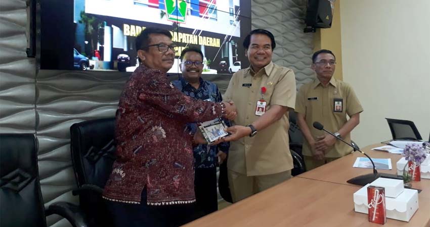 Sekda Kota Malang saat memberikan buku 50 inovasi Bapenda Kota Malang kepada perwakilan dari Pemkab Bangkalan. (gie)