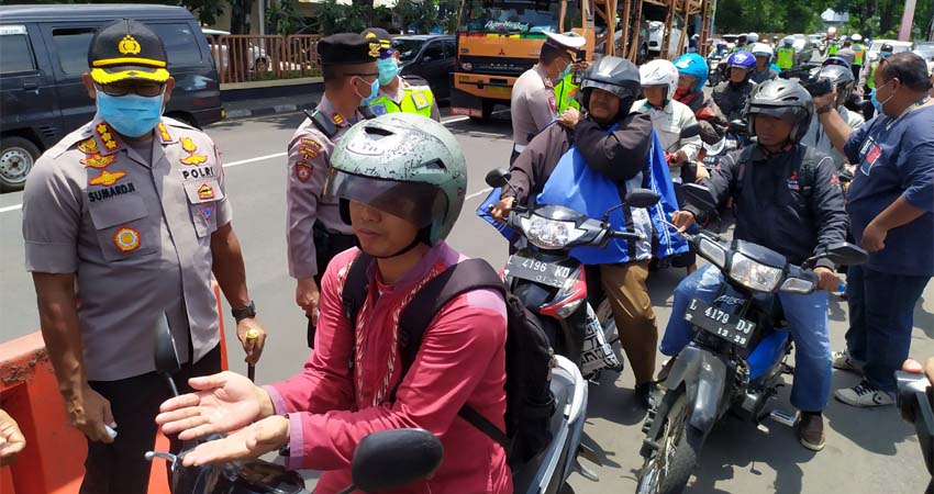 SEMPROTKAN - Kapolresta Sidoarjo, Kombes Pol Sumardji menyemprotkan hand sanitizer dan membagikan masker kepada para pengguna jalan yang melintas di depan Pos Lantas Waru bersama anggota Koramil Waru, Minggu (22/03/2020)