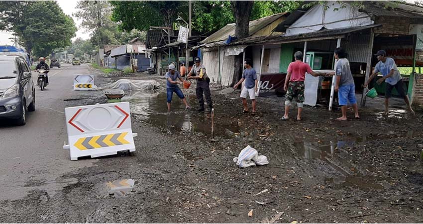 TAMBAL - Puluhan warga Desa Bakungtemenggungan, Kecamatan Balongbendo, Sidoarjo bekerja bakti bersama anggota Polsek Balongbendo menambal dan memberi water barrier di Jalan Propinsi yang berlubang, Minggu (22/03/2020)