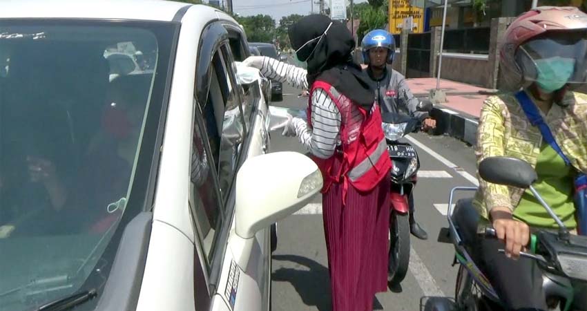 Salah satu Anggota PMI bagikan masker di Simpang 4 SMP 2 Jember. (yud)