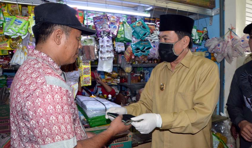 BAGI MASKER - Wabup Sidoarjo, Nur Ahmad Syaifuddin membagikan masker ke para pedagang dan pembeli di Pasar Semi Modern Tulangan, Sidoarjo sekaligus sosialisasi rencana PSBB dan kewajiban menggunakan masker, Senin (20/4/2020)