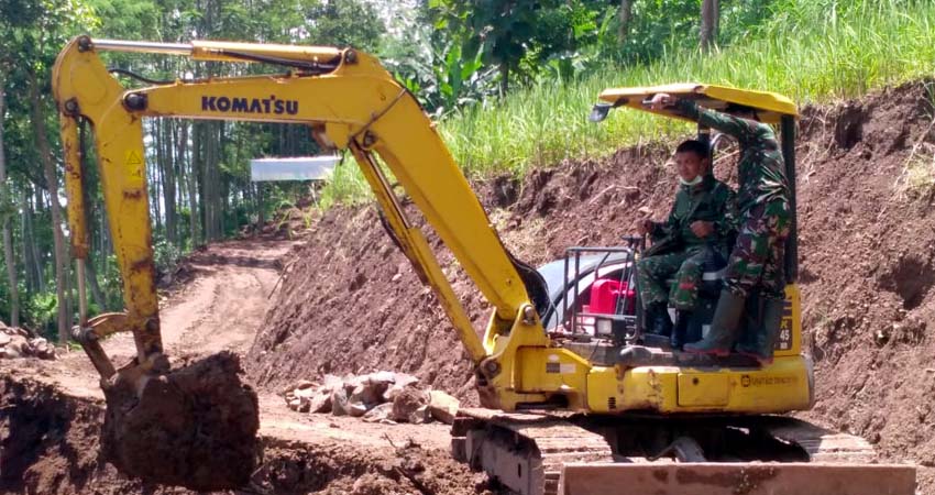 BUAT JALAN BARU: Serma Wiwit saat mengoperasikan Ekskavator di lokasi TMMD. (im)