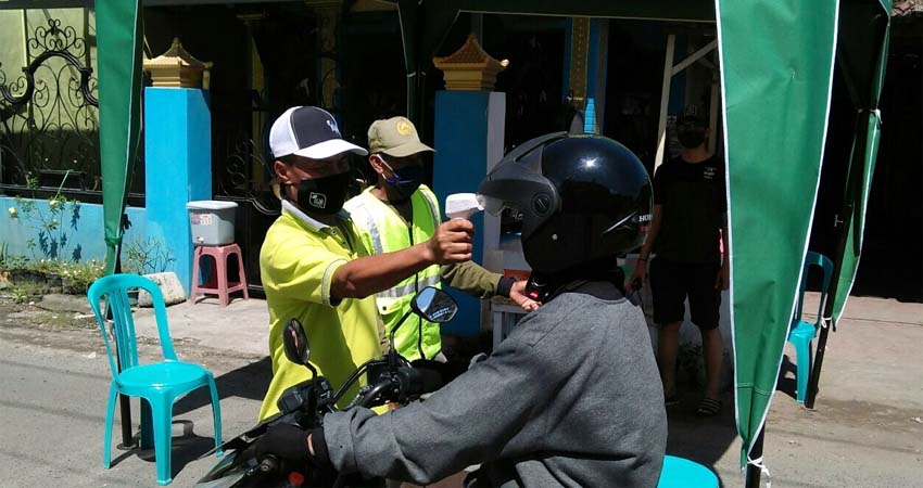 Petugas mengecek suhu tubuh warga di pos check point Desa Terik Kecamatan Krian. (par)