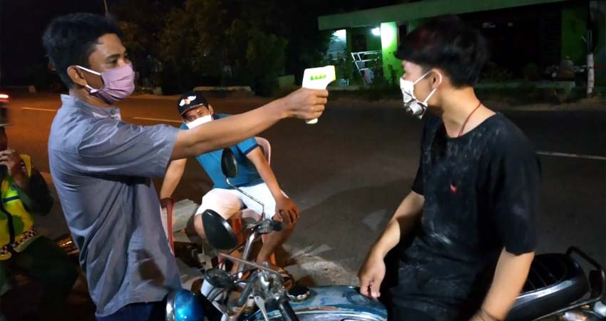 KOMPAK : Kepala Desa Ketegan Akhmad Sofi'i (topi putih) bersama tim relawan melakukan thermogund pada warga dan pengguna jalan ketika memasuki jalan raya Desa Kategan. (gus)