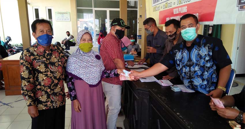 Arip Masjidin Sekretaris Desa Pilang mendampingi warganya menerima BLT DD. (par)