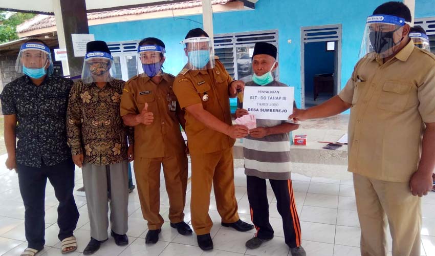 H Abdurrohman Kades Sumberejo Bersama Perangkat Saat Serahkan BLT di Dusun Sumbersari. (Sur)
