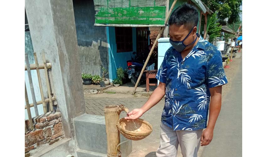 Ismanto ketua pengurus Kampung santri tangguh saat mempraktekan tempat cuci tangan dari bambu