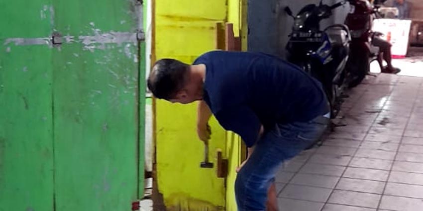 PERBAIKI - Korban pencurian Agus memperbaiki pintu di stan Warkop miliknya yang ada di Pasar Krian, Sidoarjo usai dibobol kawanan pencuri, Senin (10/08/2020)