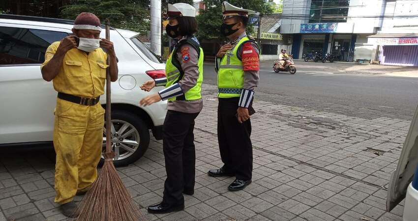 Petugas Dikyasa Sat Lantas Polresta Malang Kota saat membagikan masker kepada masyarakat yang didapati tidak memakai masker. (ist)