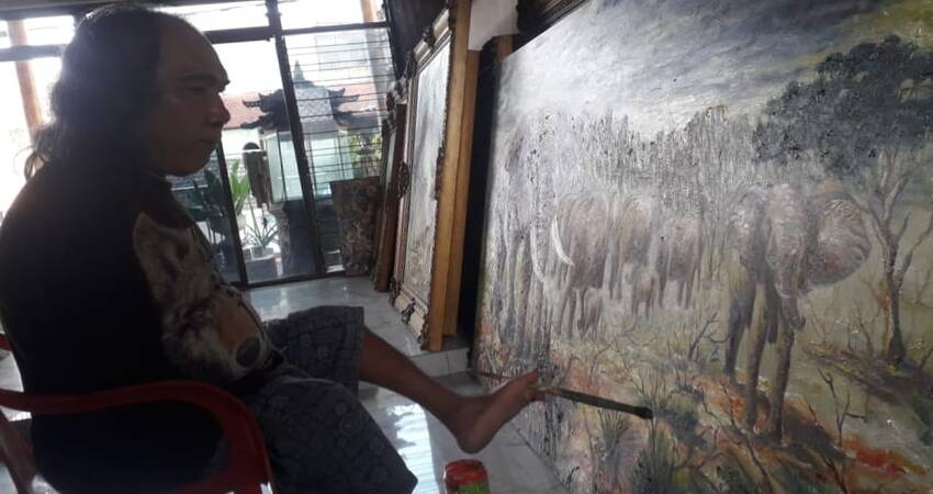 Pelukis tuna daksa Sadikin Pard saat membuat karya lukis dengan menggunakan kakinya.