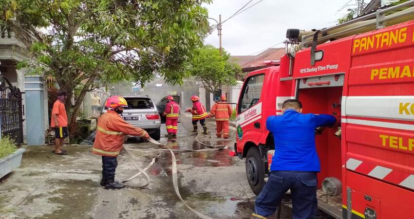 Petugas PMK Kita Malang saat memadamkan mobil BMW yang terbakar. (ist)